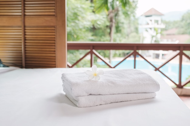 Towels and Plumeria on the bed in the luxury hotel room ready for tourist travel.