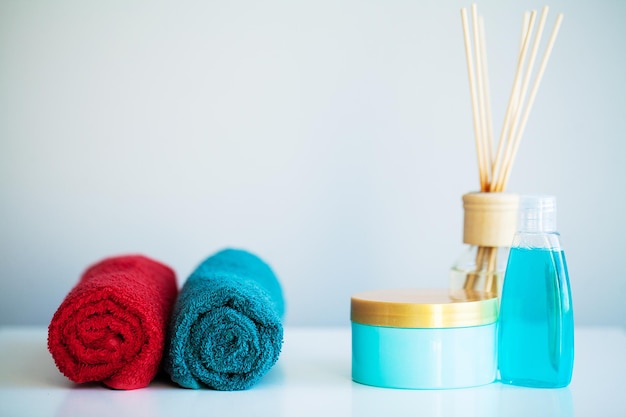 Towels and shower gel on white table with copy space on bath room background