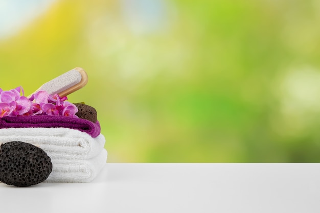 Towels with flowers on light table against blurred background