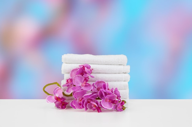 Towels with flowers on light table against blurred background