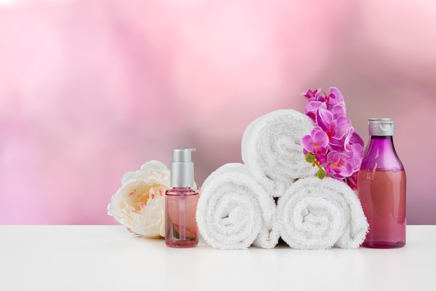 Towels with flowers on light table against blurred background