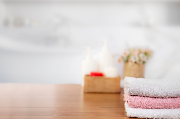 Towels on wooden top table with copy space on blurred bathroom.