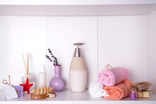 Towels in a wooden tray with aroma chopsticks, candles, seashells, massage washcloths