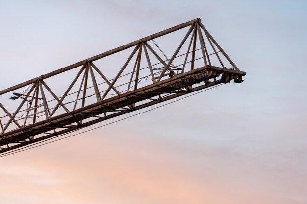 Tower crane on the background of the sky at sunset The boom of a construction crane closeup