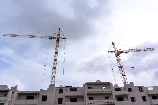 Tower crane and building under construction against blue sky. Copy space photo of the construction