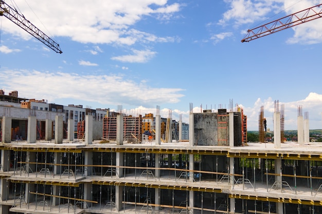 Tower crane at high concrete residential building under construction. Real estate development concept.