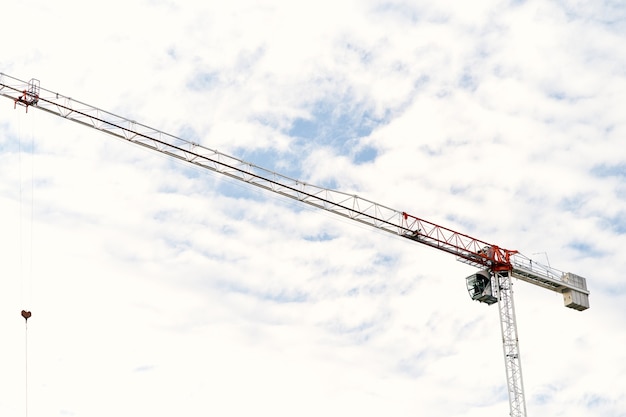 Tower crane with leftpointing boom against a blue sky with white clouds closeup
