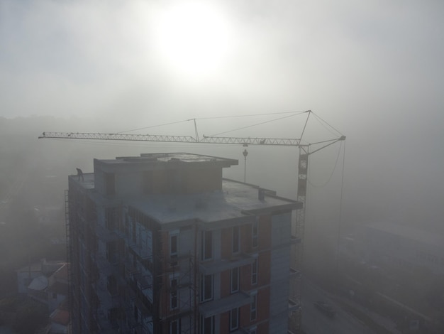 Tower cranes on a construcion site with dense fog aerial view