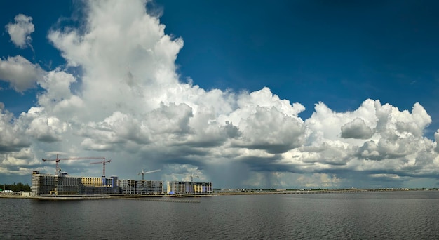 Tower cranes and frame structure of high residential apartment buildings at construction site on sea shore Real estate development