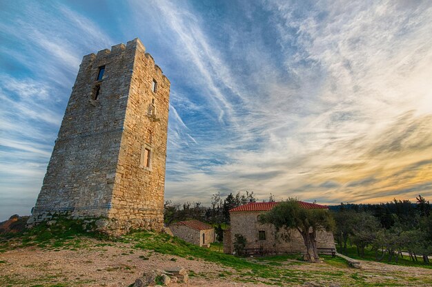 Photo a tower on a hill with a cloudy sky in the background