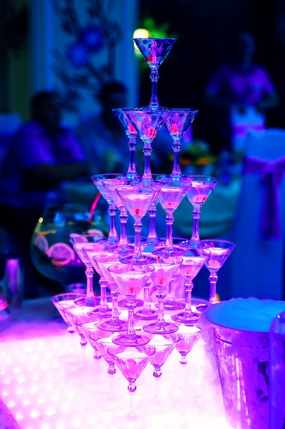 Tower of Martini glasses in restaurant with ultraviolet illumination