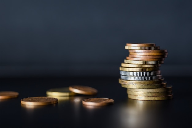 Tower of metal coins on black background.