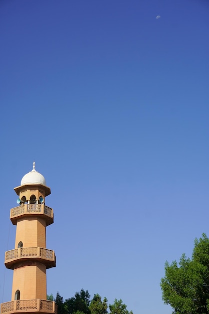 A tower with a blue sky and the moon in the background.