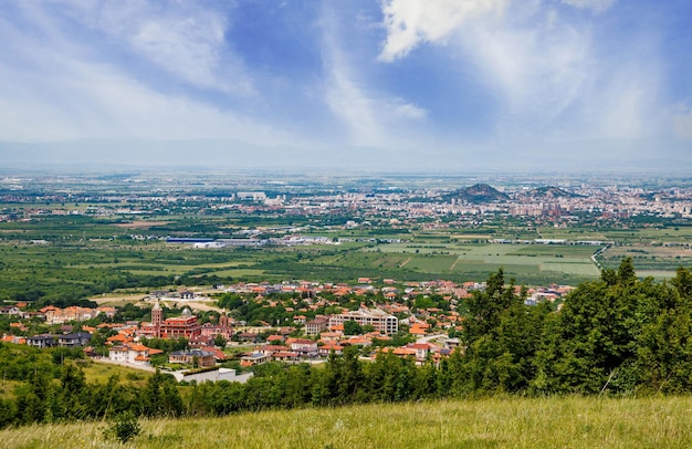 Town Plovdiv with houses and fields against backdrop of Rhodope Mountains and hills covered with forests and cloudy sky