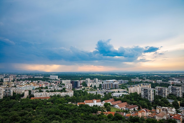 Город Пловдив с домами и полями на фоне Родопских гор и холмов, покрытых лесами и облачным небом
