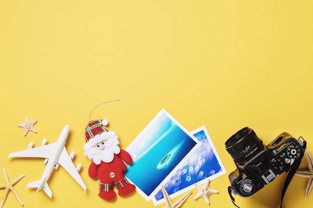 Photo toy airplane photos and camera on a yellow background with copy space christmas travel planning concept