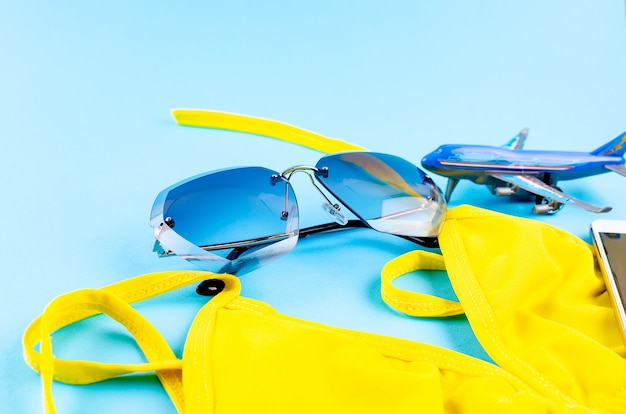 Toy airplane, swimsuit and glasses on a blue table