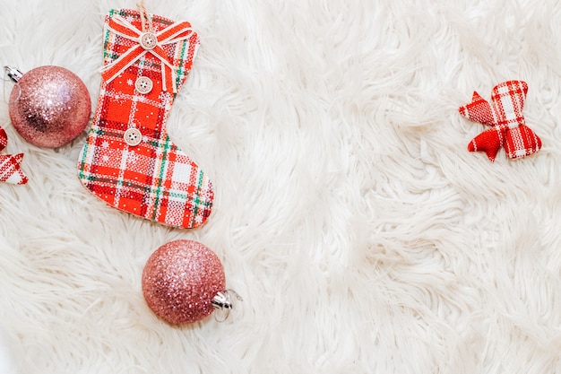 Toy balls with christmas sock on a fluffy white background.