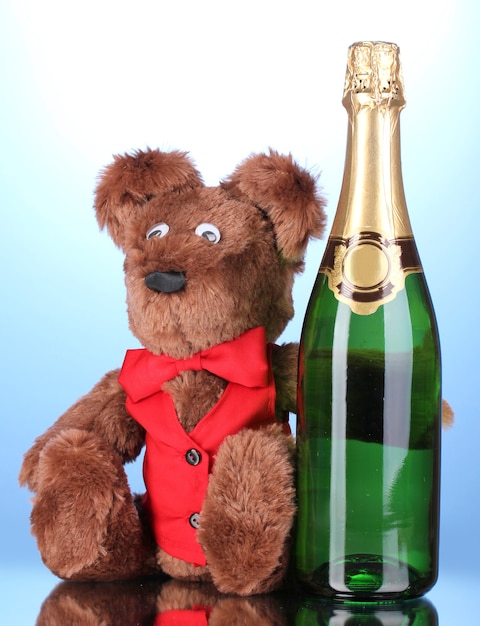 青い背景のおもちゃのクマとシャンパンのボトル