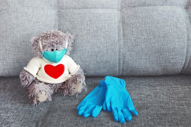 A toy bear in a medical mask next to medical gloves