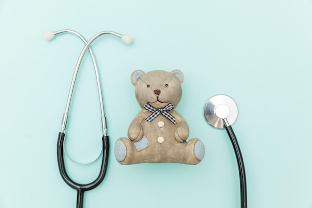 Giochi l'orso e lo stetoscopio dell'attrezzatura della medicina isolato sul blu pastello