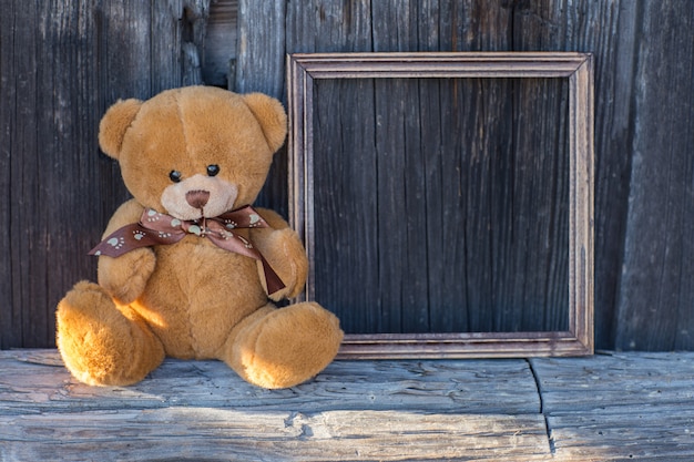 toy bear sits on a table and next to a wooden empty frame