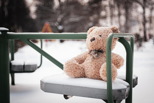 장난감 곰은 겨울에 어린이 놀이터에 방치되었습니다.