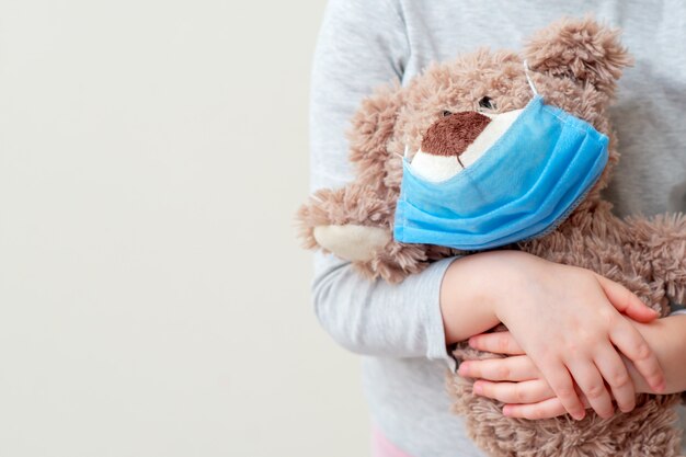 Orso giocattolo con maschera protettiva nelle mani del bambino