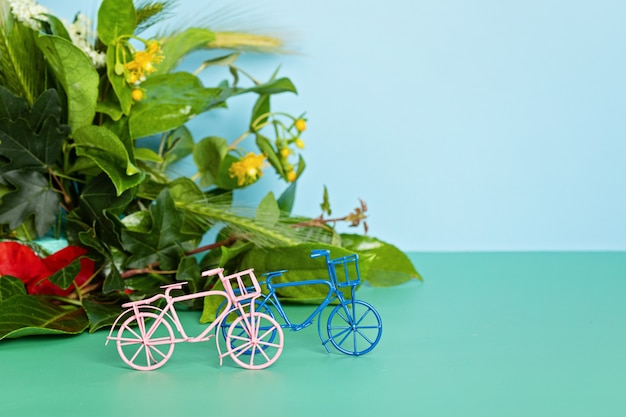 おもちゃの自転車と緑の葉。カーフリーデー、世界自転車デーのアイデア