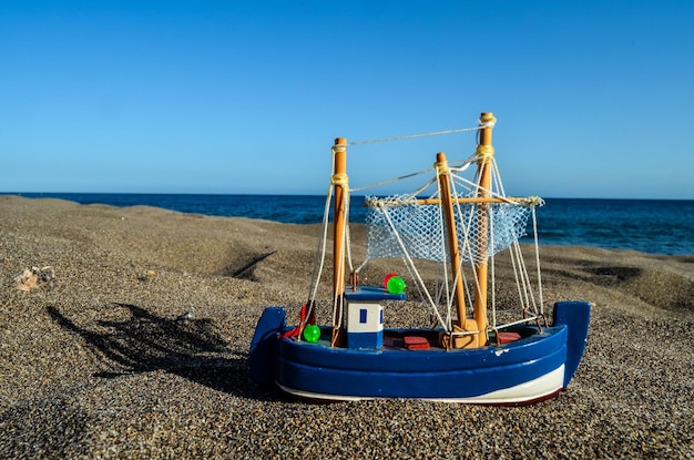 Игрушечная лодка на песчаном пляже