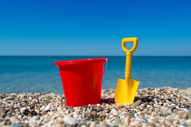 Foto benna e vanga del giocattolo sulle pietre della spiaggia