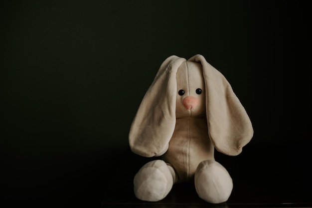 Toy bunny on table against dark background Time to visit child psychologist