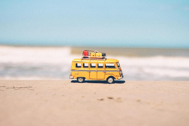 Foto autobus giocattolo sulla sabbia sulla spiaggia contro il cielo