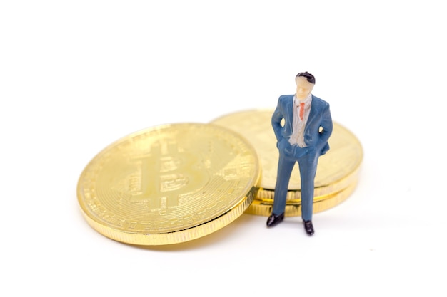 Toy businessman and Bitcoin on white background