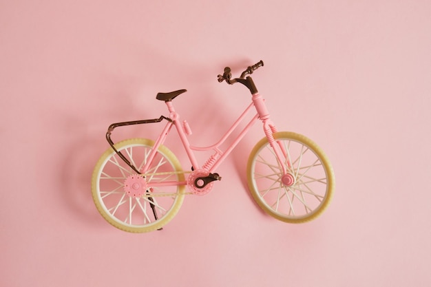 Toy bycicle on pink background copy space