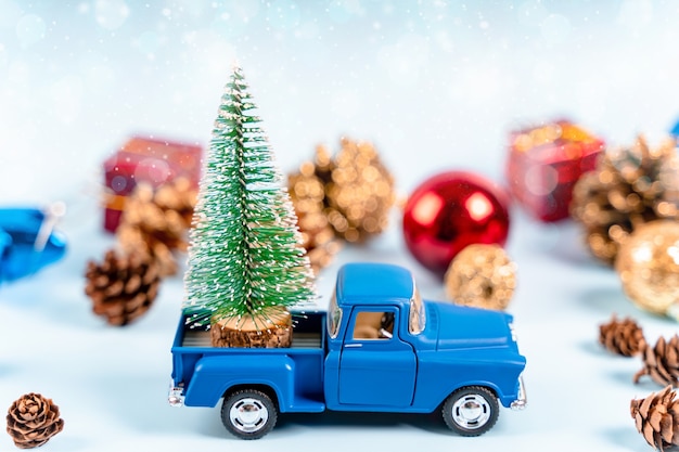 장난감 자동차는 파란색 배경에 크리스마스 트리를 운반합니다 새해를 위한 멋진 배경