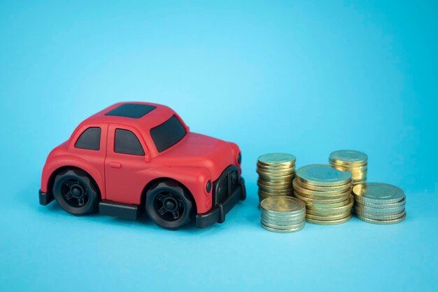 Toy car and coins on an isolated blue background