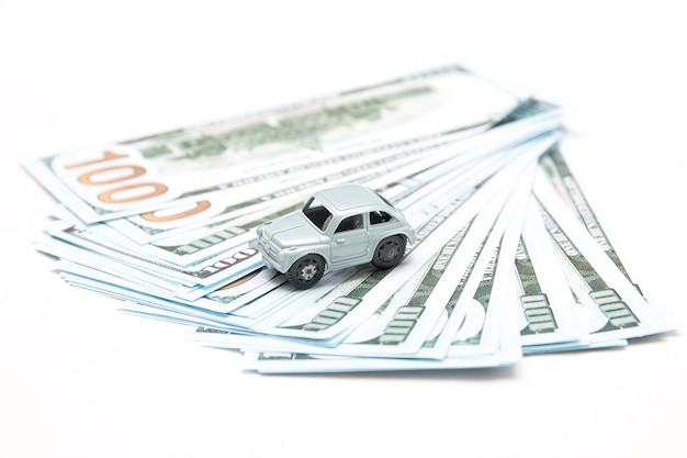 Toy car on dollar bills on white