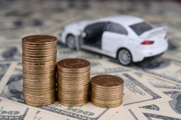 Toy car model at the stacks of golden coins lies on many dollar bills