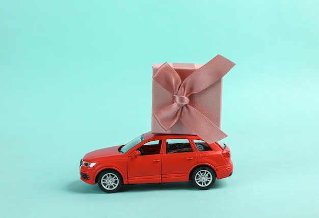 Photo toy car model with a gift box on blue background delivery holiday concept