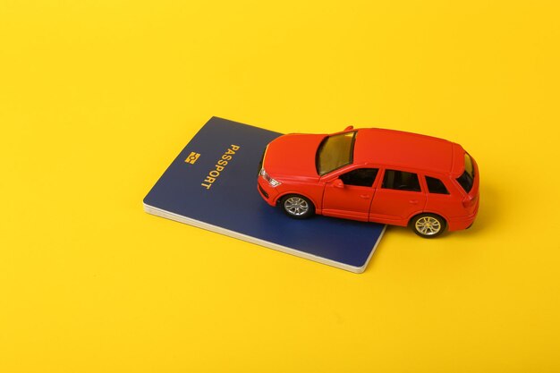 Toy car model with a passport on a yellow background Travel concept