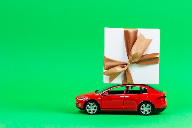 Toy car with christmas present against green background