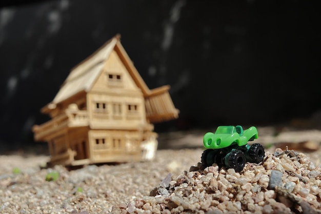 A toy car with a wooden house in the background