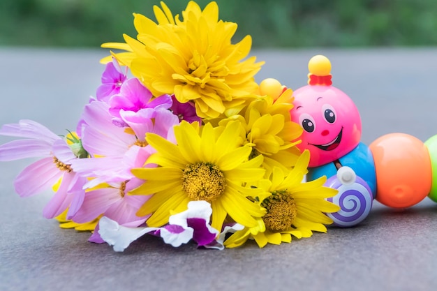 Toy caterpillar crawls to a bouquet of wildflowers, close-up