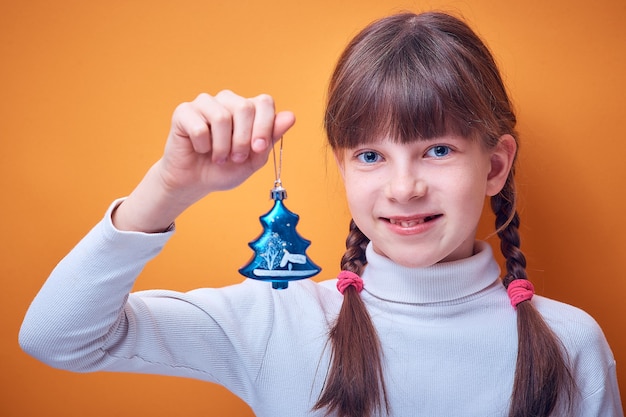 Toy for the Christmas tree at the Caucasian girl in the hand on a colored