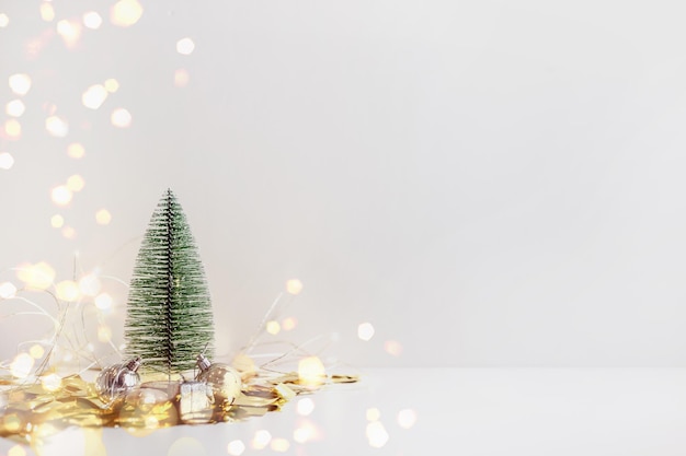 Toy Christmas tree with balls, gift and bokeh lights on white background with copy space for text. New year holiday concept