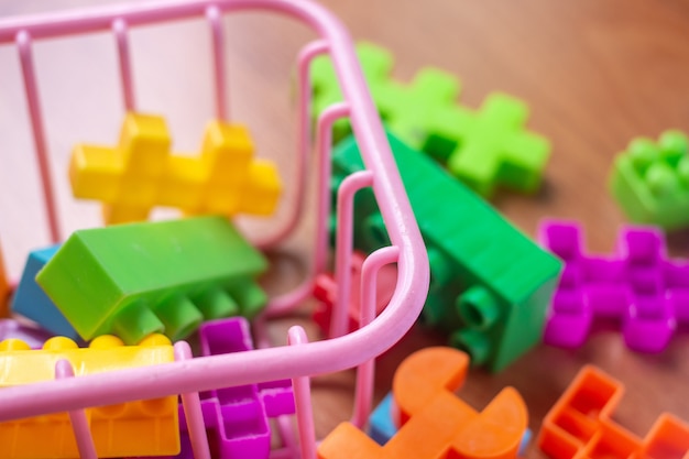 Toy colorful plastic blocks on wooden floor background