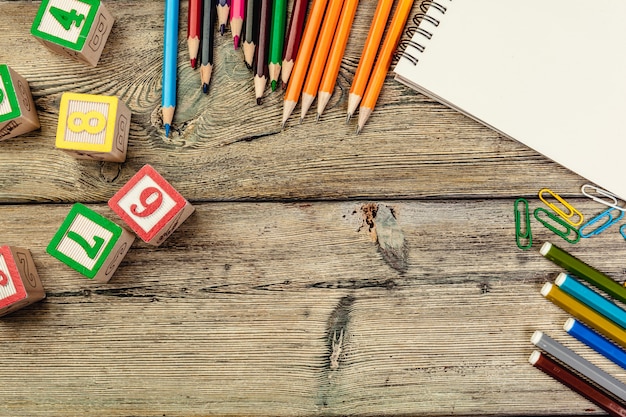 Toy cubes with letters and blank notebook on wooden background, copy space