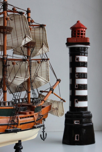 Игрушечный фрегат с тканевыми парусами повернулся носом к миниатюрному маяку Стоковое Фото