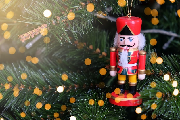 Toy funny nutcracker hanging on Christmas tree.